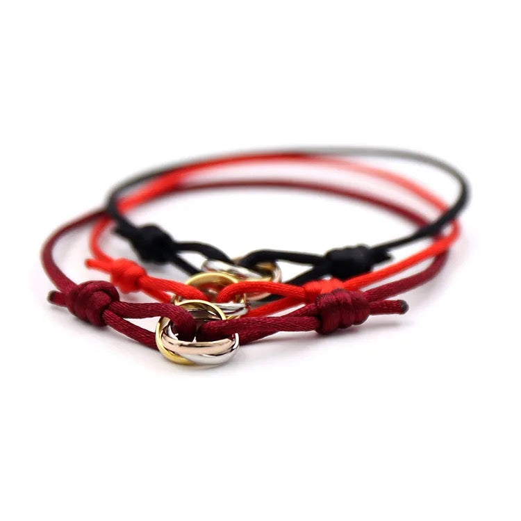 Set of three adjustable cord bracelets (black, red, burgundy) with gold and silver interlocking ring charms. Friendship or stacking jewelry.