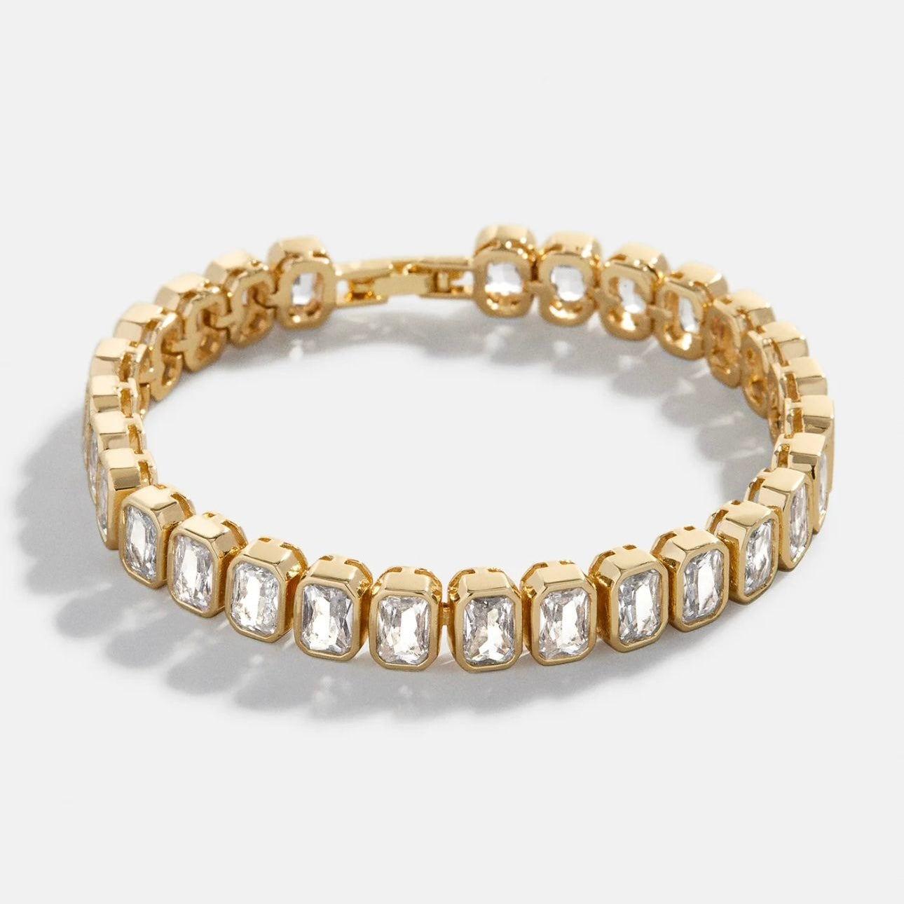 Pulsera tenis de oro con eslabones de piedras de corte esmeralda y cierre de seguridad. Joyería de lujo elegante y atemporal.