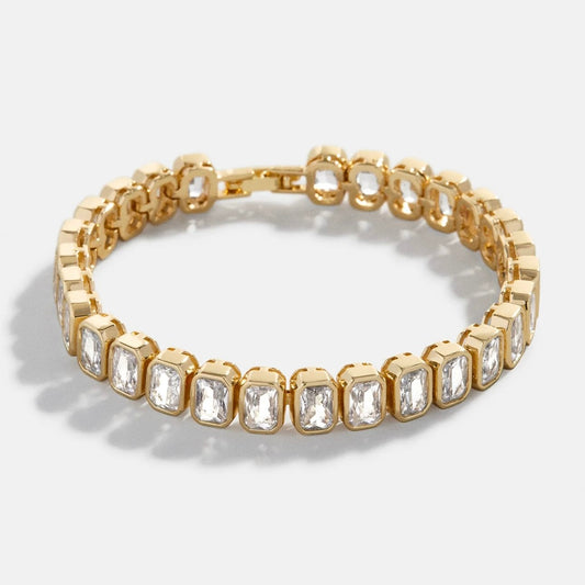 Pulsera tenis de oro con eslabones de piedras de corte esmeralda y cierre de seguridad. Joyería de lujo elegante y atemporal.