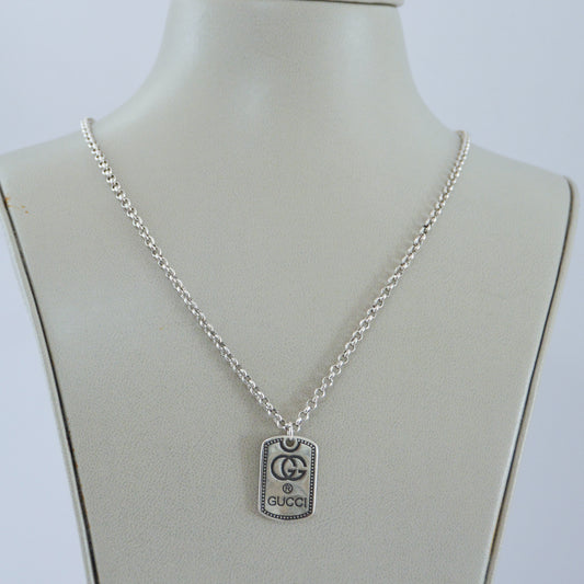 Silver Gucci dog tag pendant necklace with logo engraving on chain displayed on jewelry bust stand